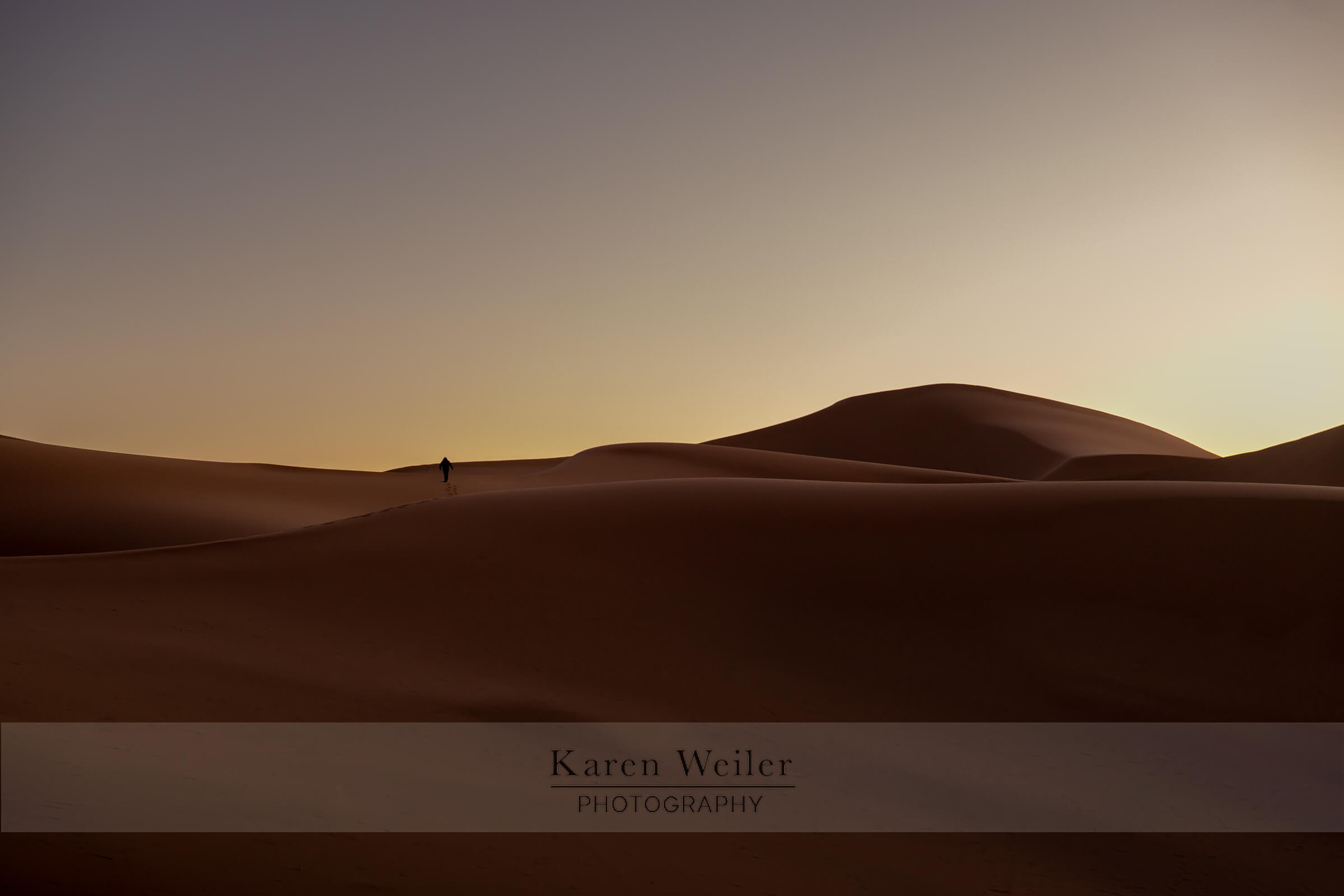 Lone figure in Sahara desert, Morocco, at sunrise